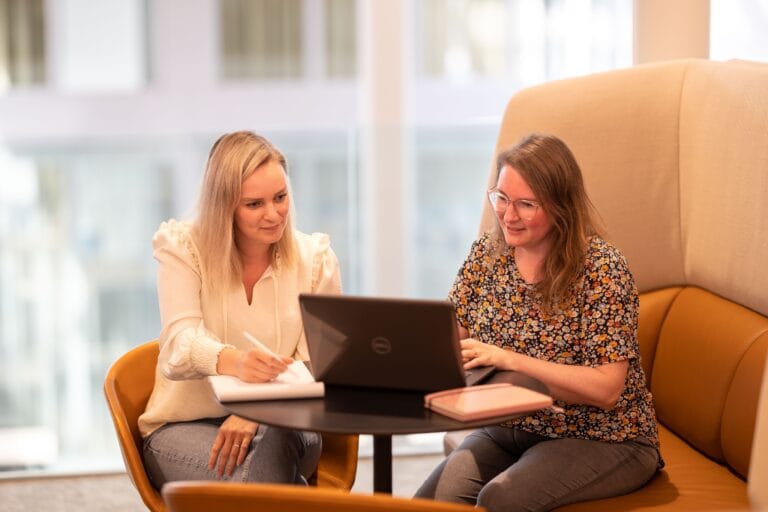 Twee vrouwen werken achter de laptop in een openbare ruimte.
