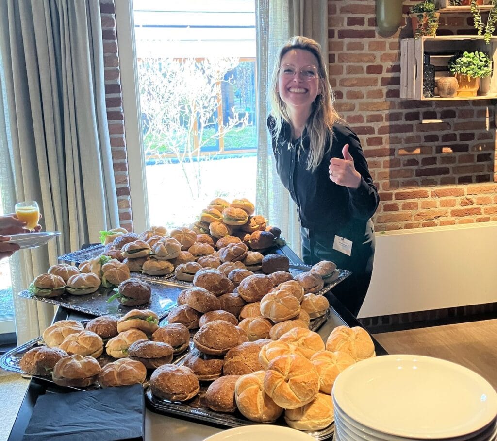 Medewerker steekt haar duim op, lacht en kijkt naar de camera.
